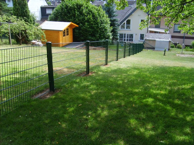 Moosgrüner Gartenzaun an einer Grundstücksgrenze